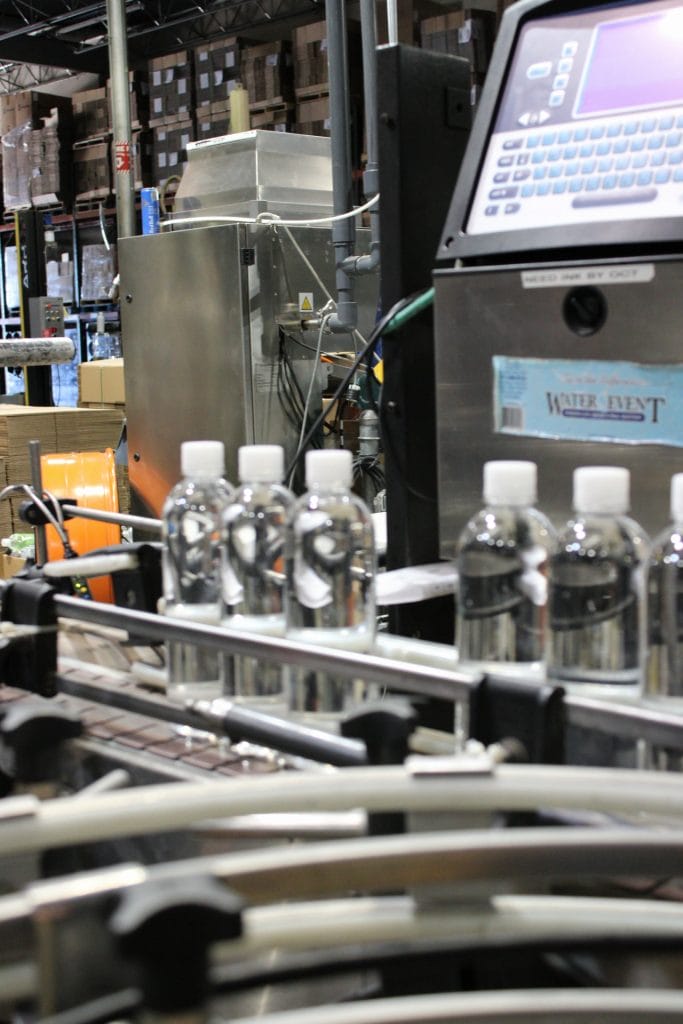 Custom water bottles moving through Texas Water House’s production equipment